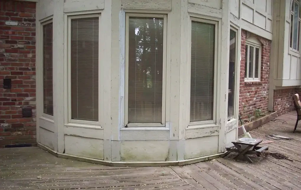 Bay window with peeling paint, moss, and weathered wood before Guy Painting repair