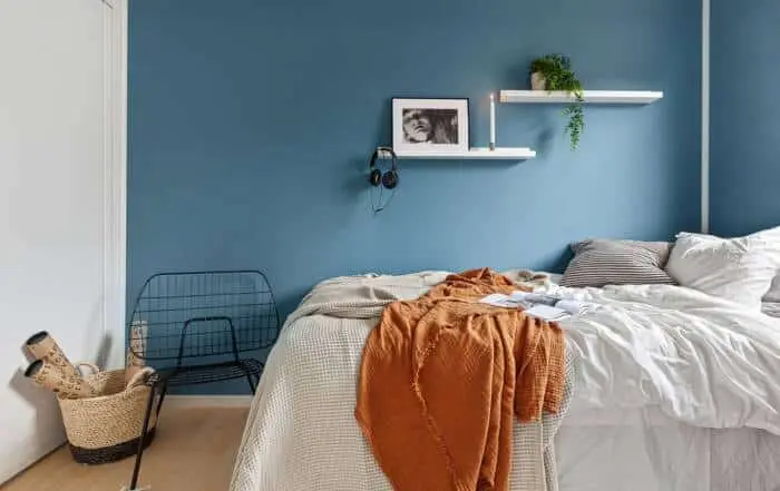 Bedroom with a smooth deep blue accent wall complementing light bedding and minimalist decor.