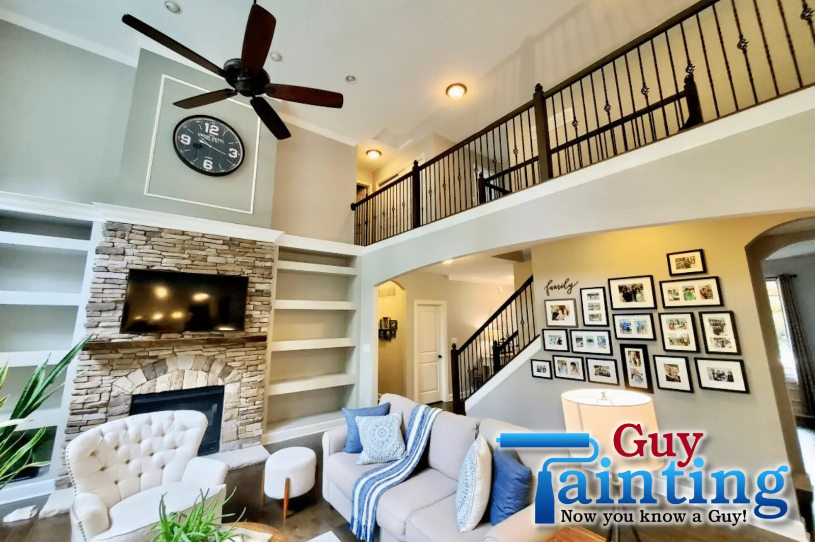Two-story living room painted light French gray with a dark fireplace