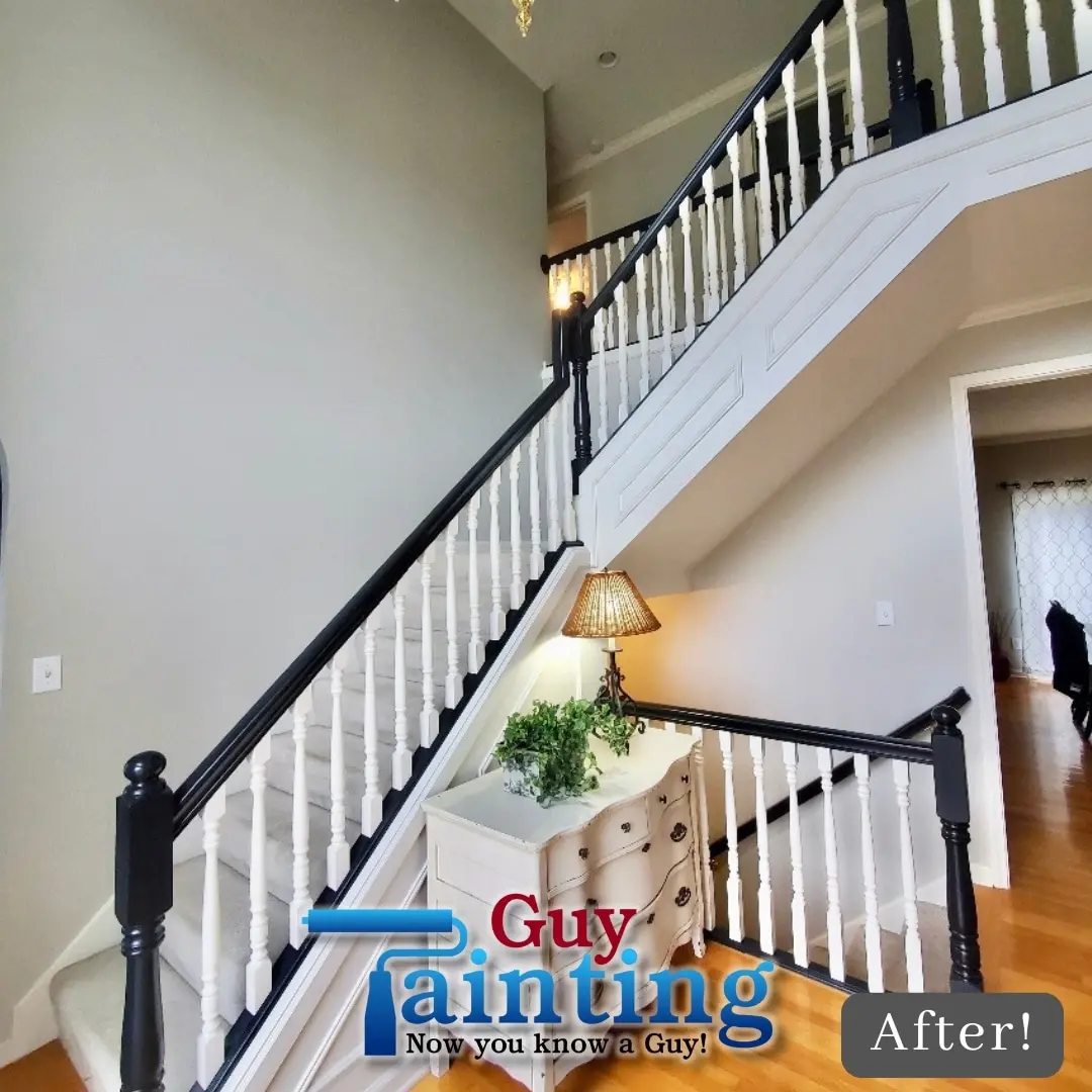 A bright and modern residential foyer featuring a high-contrast black banister and crisp white spindles after a professional renovation. This stunning visual represents the quality of interior painting Indianapolis services in Geist. Guy Painting focuses on clean lines and premium finishes to completely revitalize the home's entryway, as seen in this final "after" shot showcasing the elegant transition from natural wood to a contemporary look.